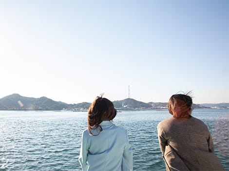 クルーズ船のデッキから、海や島々の景色を眺めている二人組の女性