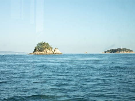 クルーズ船の船内から窓越しに見える島や海原を撮影した様子