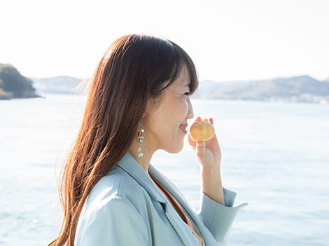 瀬戸内海を背景に、魚のお菓子と楽しそうに撮影する女性