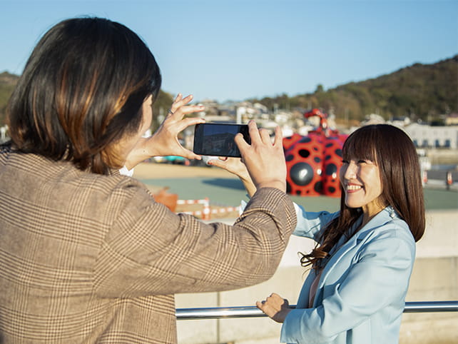 赤いかぼちゃのオブジェと一緒に写真を撮影している女性